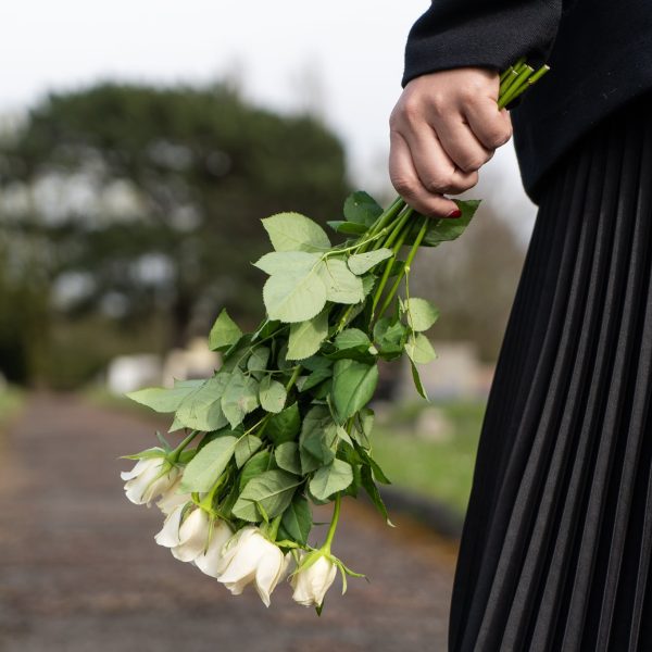 female carrying bouquet of white flowers at a funeral