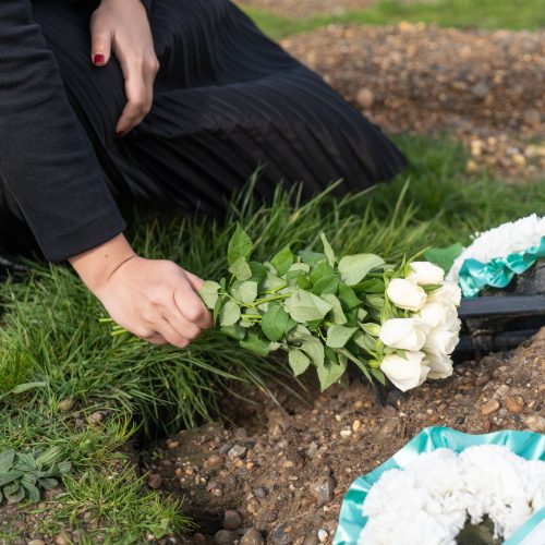 female laying flowers at a grave for funeral