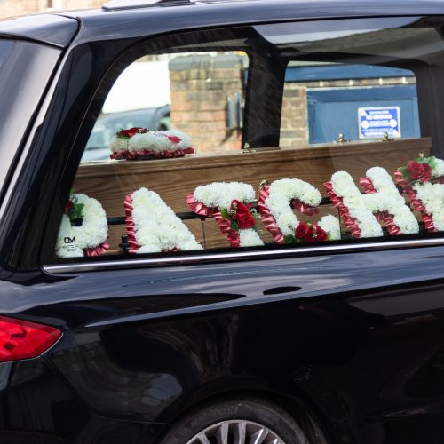 funeral car carrying coffin and floral tributes