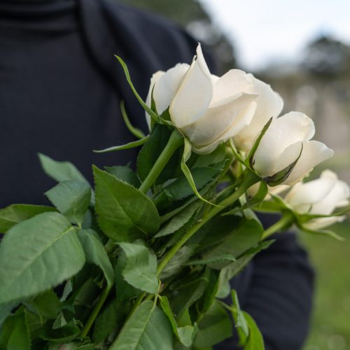 woman at funeral holding white rose flowers