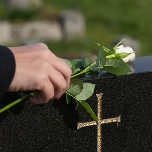 woman laying flower on head stone